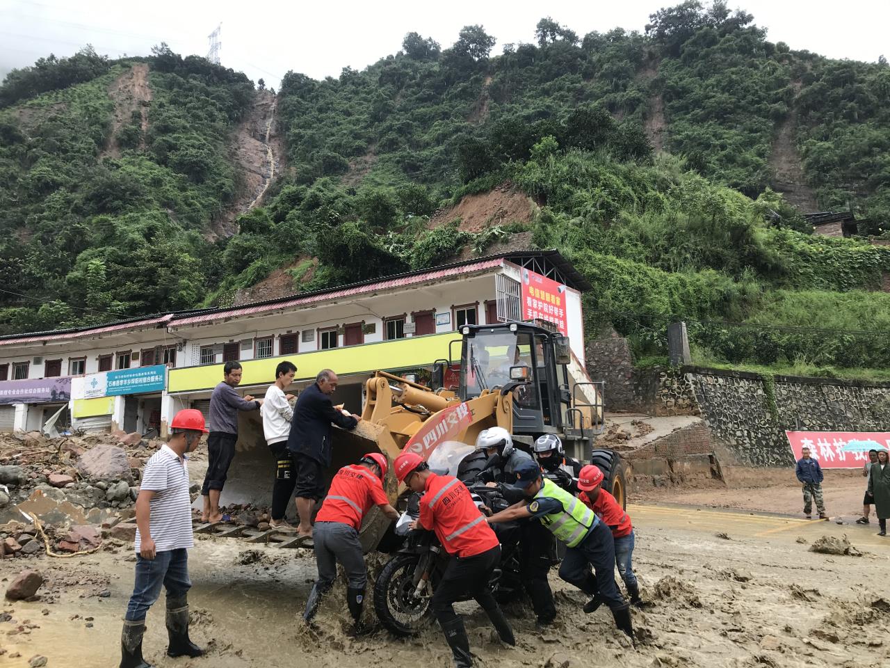 8月18日，搶險人員與民警幫助被困群眾的摩托車通過涉水路面.jpg